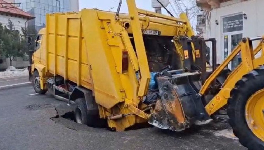 Momentul în care o mașină de gunoi este „înghițită” de o groapă apărută în asfalt, în centrul orașului Galați