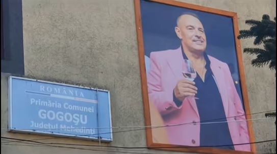 Tablouri cu edilul mort al unei comune din Mehedinți, cu paharul de vin în mână, la intrarea în primărie
